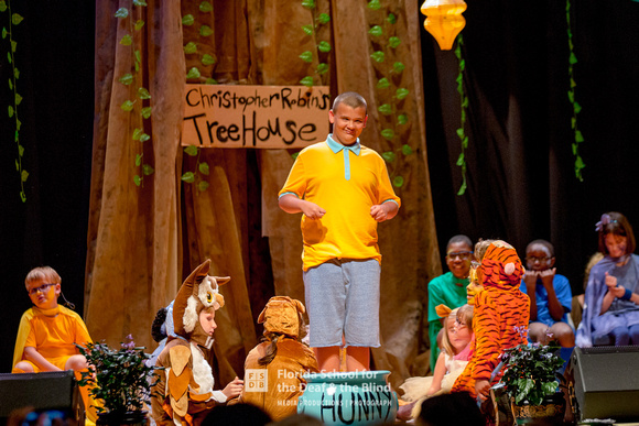 Christopher Robin stands on stage, surrounded by all the characters.