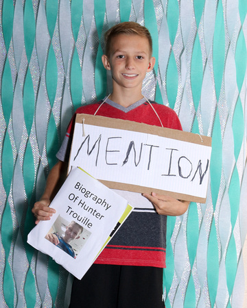 Boy holding a book titled "Biography of Hunter Trouille" and his word is Mention.